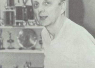 Ron Underwood at Beyer High School in the 1980s, seated in front of a display of student trophies that represent decades of success in speech and debate.